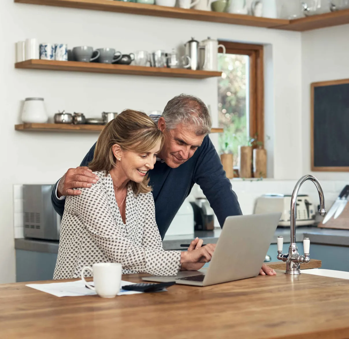 A couple sit at their kitchen table while looking at legal documents on their laptop