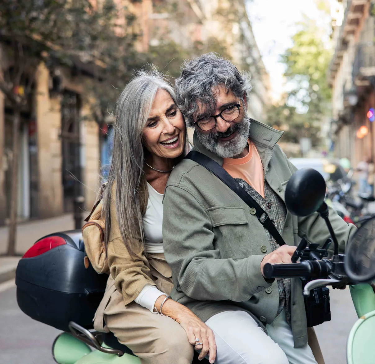 A husband and wife take a break while driving their vespa through a European village