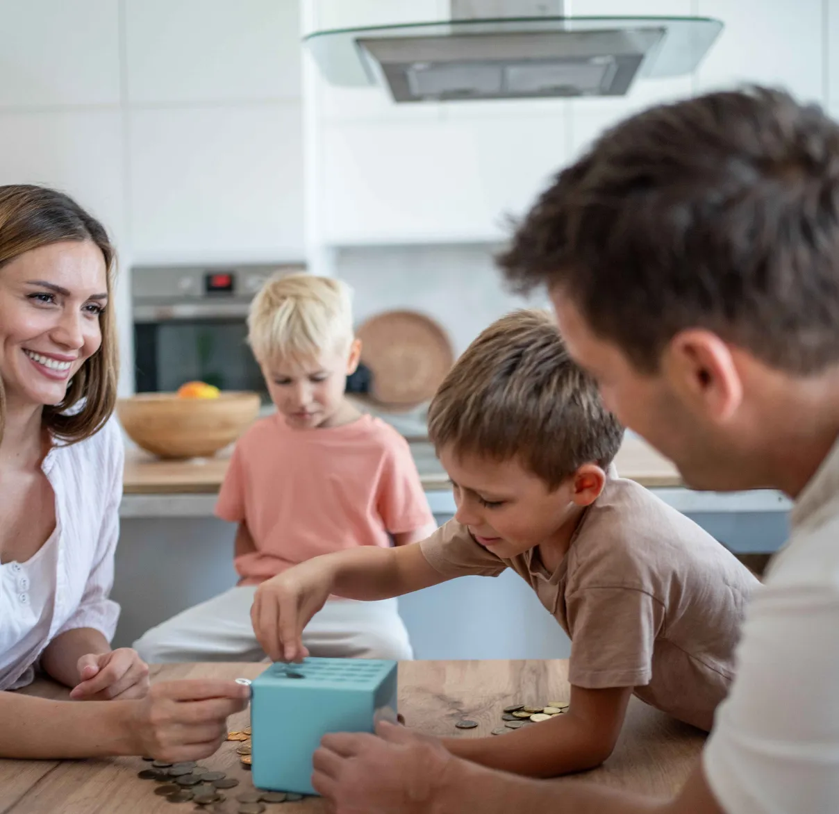 A mother and father sit at the kitchen table playing a game with their two young sons