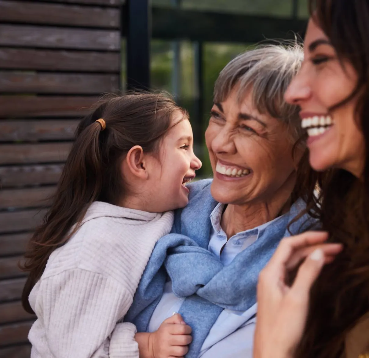 A grandmother, mother and daughter hug and laugh together