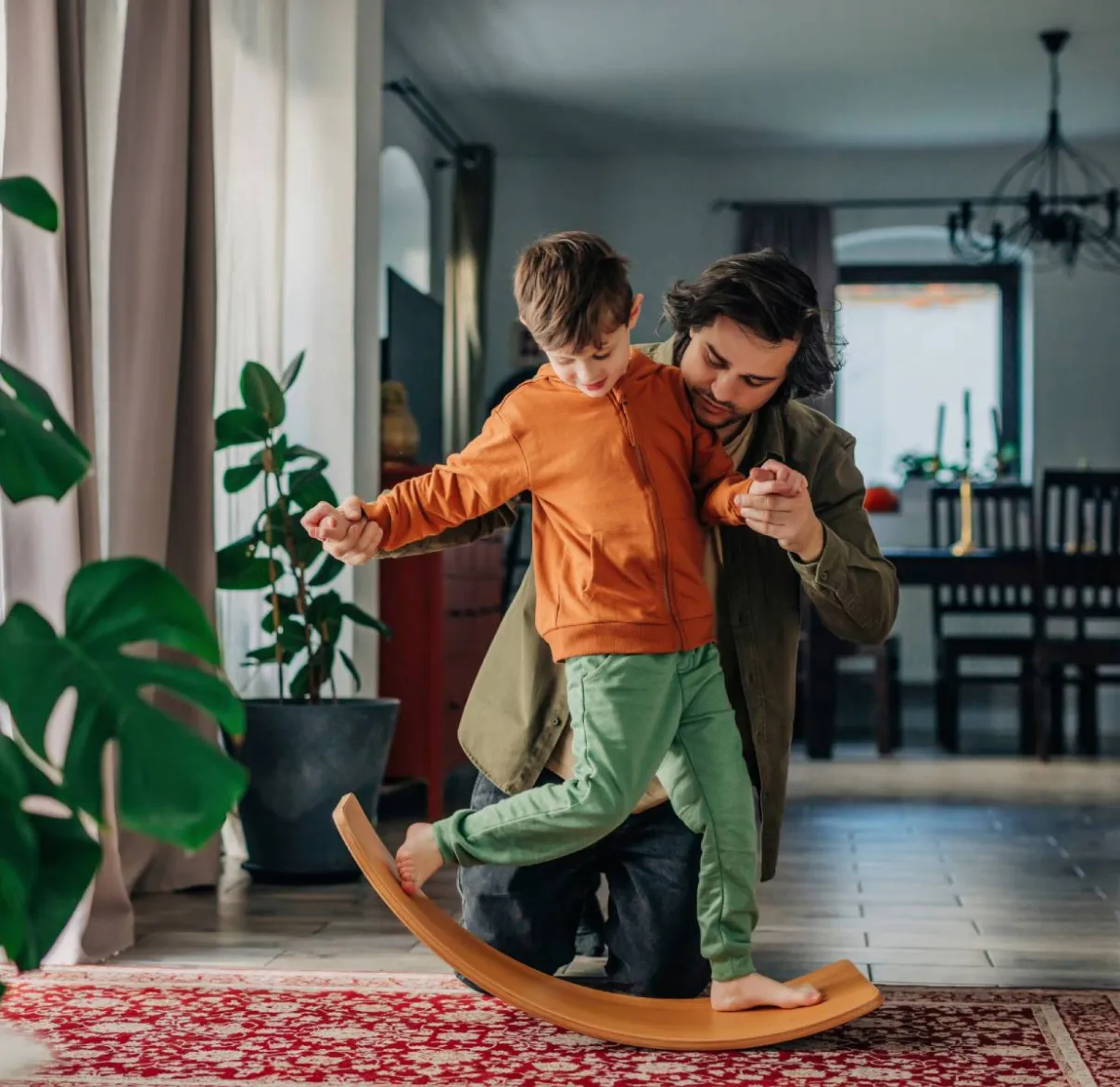 A father and son play together at home on a balance board