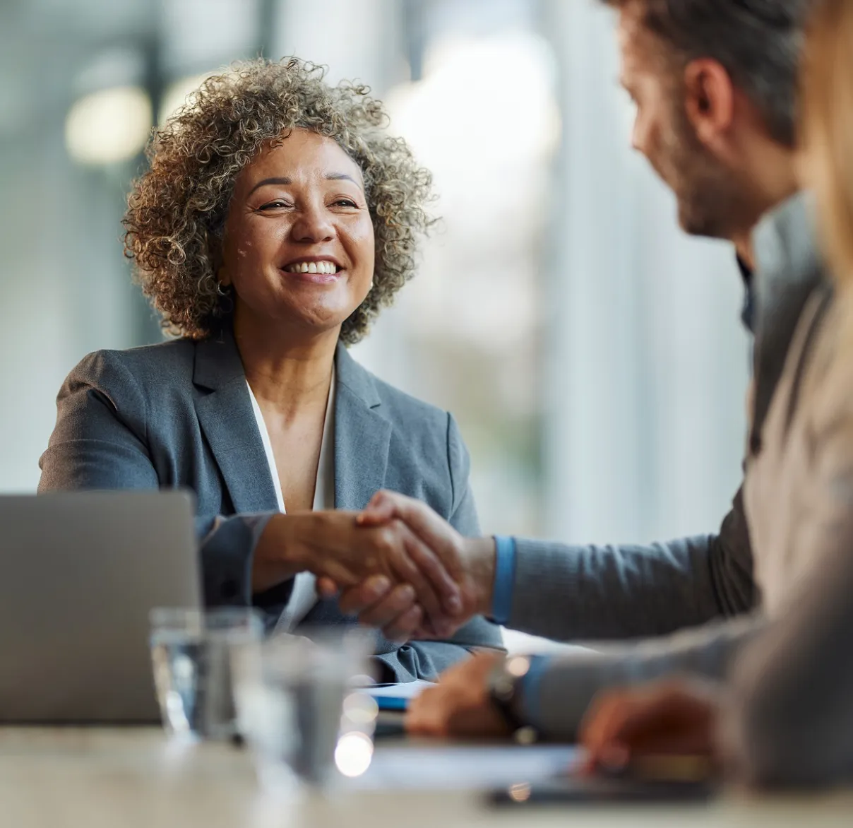 a woman sat down at a table shaking hands with a man and woman