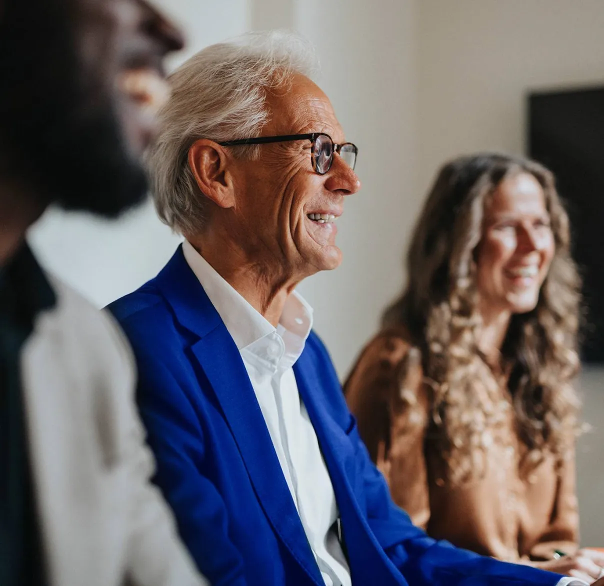 Three financial advisers laugh together while in a meeting