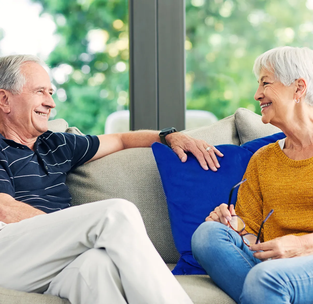 A couple laugh together while sitting on their sofa at home