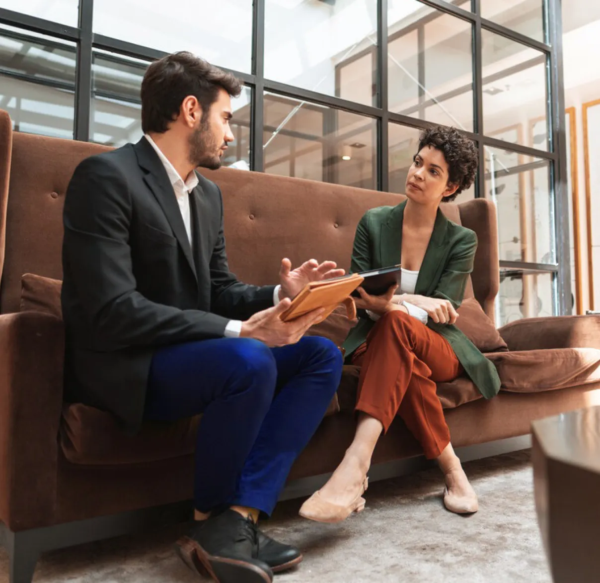 A man and a woman have a discussion on a sofa in a work office