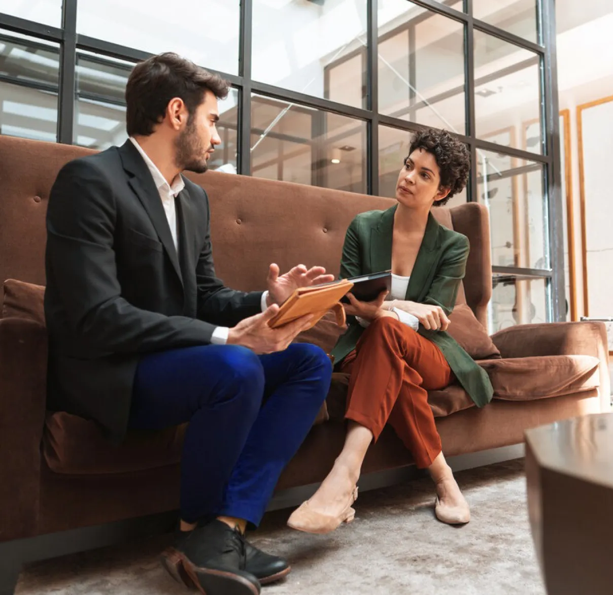 A man and a woman have a discussion on a sofa in a work office