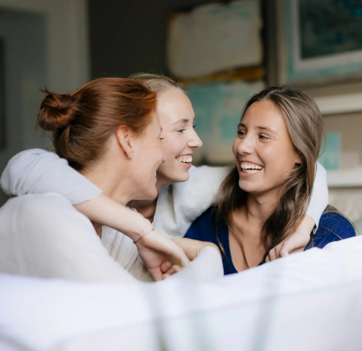 Three people sitting together on a sofa at home, representing conversations about future goals and the importance of saving for retirement