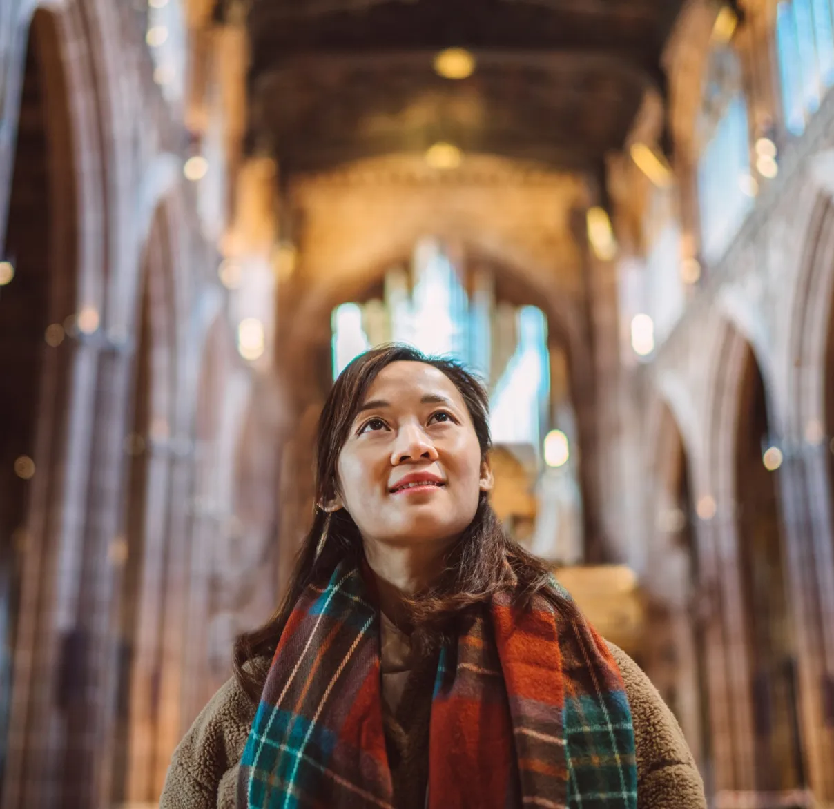 A woman looks up towards the ceiling of a large cathedral in the UK
