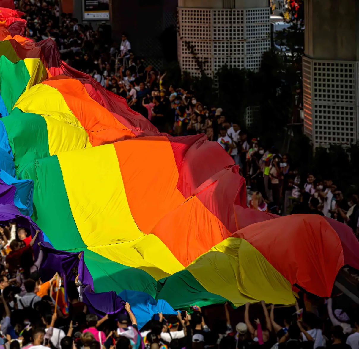 Pride flag is being carried down the street by a crowd