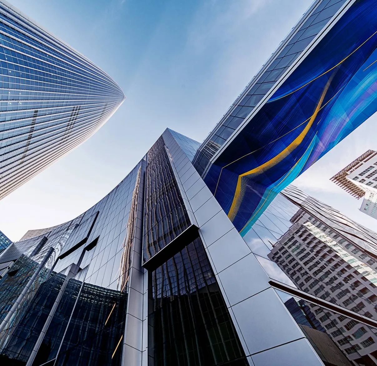 Looking up through skyscrapers in a city towards a blue sky