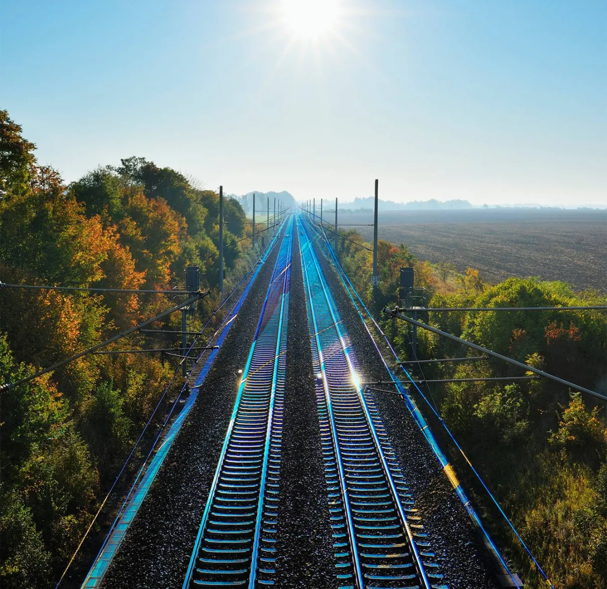 Looking down on sun-drenched train tracks cutting through the countryside