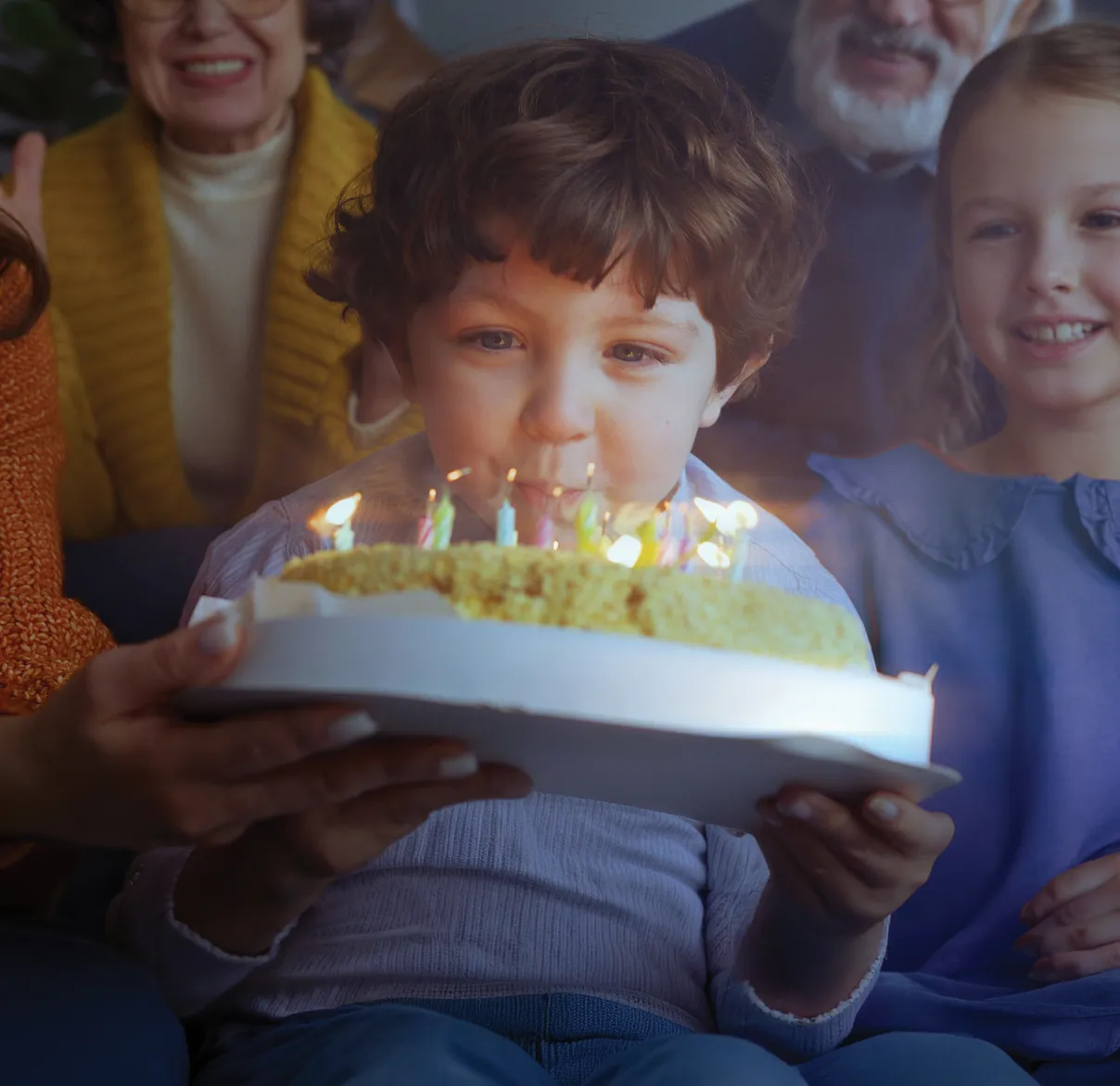 A young boy leans in to blow out birthday candles