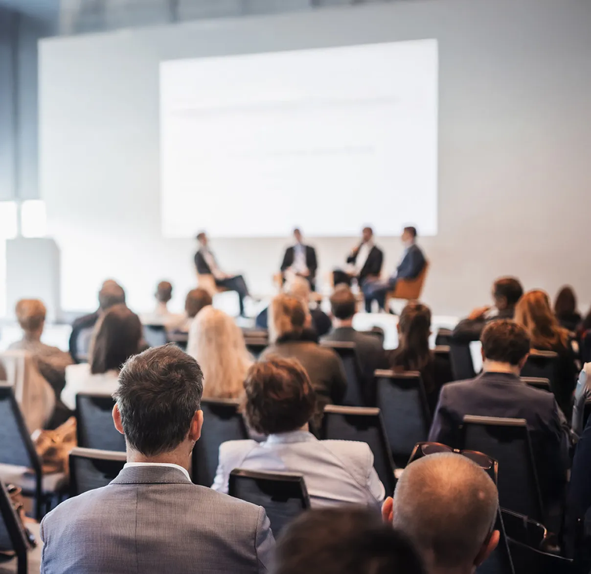 A room of people listening to a panel at an Annual General Meeting