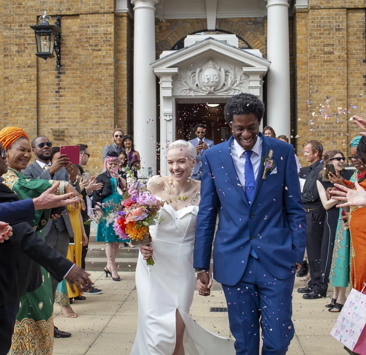 Newlyweds walk out of their town hall to a crowd throwing rice and flowers at them