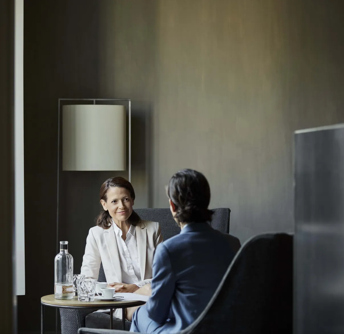Two professionals speaking over coffee in a private meeting space