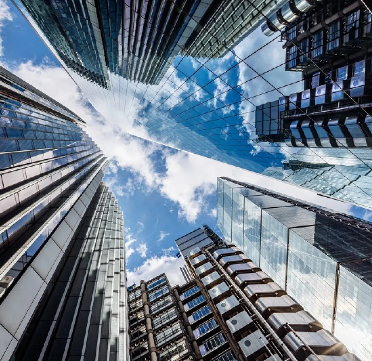 Looking up towards the sky between the glass-faced skyscrapers in the City of London's Square Mile