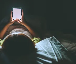 Person looking at mobile device in bed