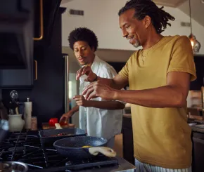 A father and son cook eggs together in the kitchen