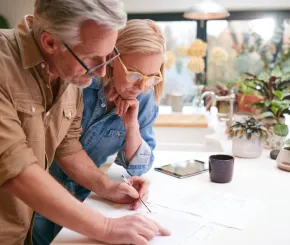 A couple review documents spread out across their kitchen bench together