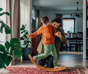 A father and son play together at home on a balance board