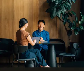 Two people talking at a table with an ipad