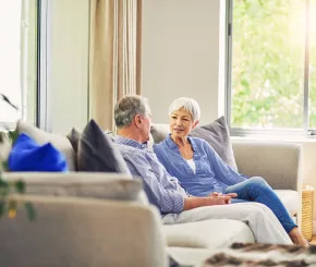 A couple having a conversation on their sofa at home
