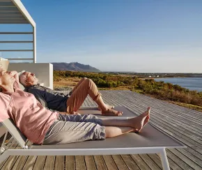 A couple recline on sun loungers in the sun while on holiday