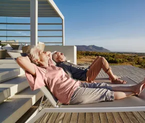 A couple recline on sun loungers in the sun while on holiday