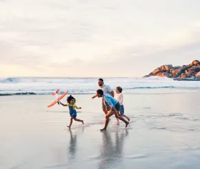 A family play together in the wash of the sea on a beach
