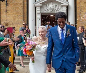A young couple just married, leaving the registry office as family and friends throw confetti