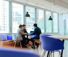 Three colleagues meet in a corporate meeting area to look at statistics on a laptop