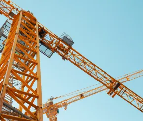 Looking upwards at a yellow crane in use at a construction site