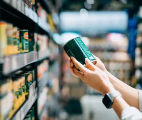 Close up of a woman holding a tin can and grocery shopping in a supermarket