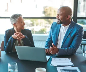 Man and woman sitting and talking in front of a laptop