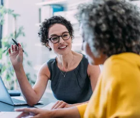 An adviser speaking with a client gathered around a laptop