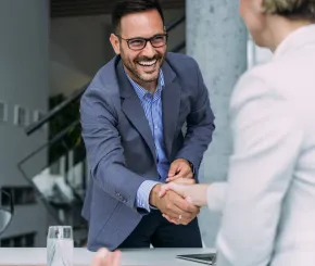 A smiling financial adviser shakes hands with a woman during a meeting