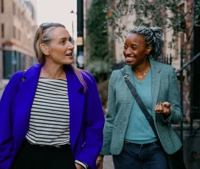 Two women who are friends, walking down the street and having a conversation