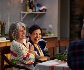 Mother and daughter laughing together at the dining table