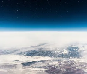 Starry sky above clouds and snow-covered mountains, viewed from space