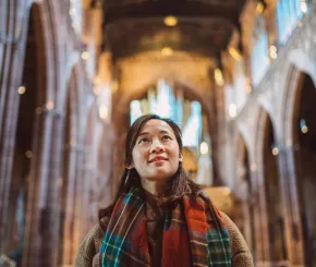 A woman looks up towards the ceiling of a large cathedral in the UK