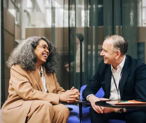 A solicitor laughing and joking with client while they are sat in chairs with tables