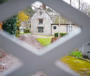 A view of a brick house through a criss-cross gate in the foreground
