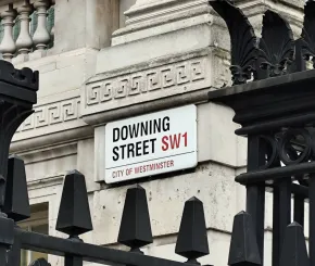 Downing Street street sign on building next to a lamp post
