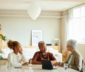 A mother and daughter speak with a financial adviser at their kitchen table