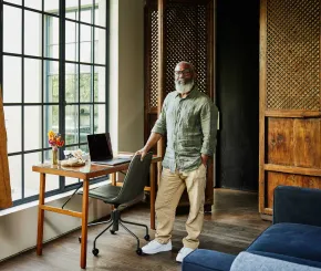 An entrepreneur with an eye for luxury looks at the camera while standing in his minimalist home office