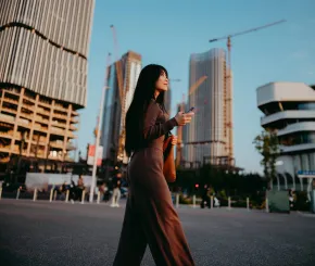 A woman walks through a city under construction while holding a phone