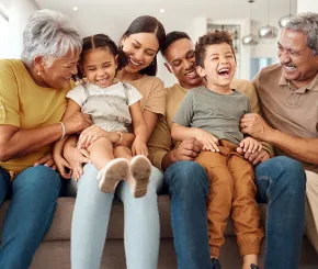 multi-generational family together on a sofa laughing and smiling