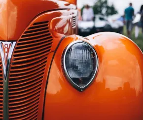 A close-up of a classic old car in a bright orange paint job