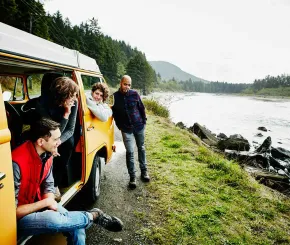 Young family with teenagers on a campervan holiday by the river