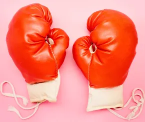 Red boxing gloves against pink background